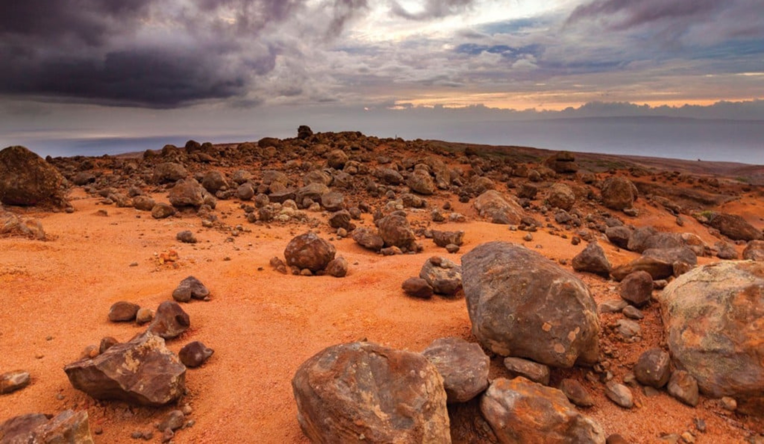 Red dirt and rocks as you can see the grey clouds in the background and in the sky.
