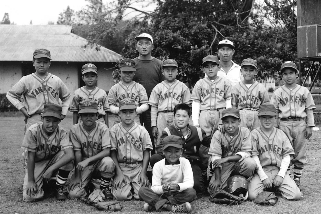 Black and white photo of Yankee baseball players posing for a team photo. The players are dressed in their iconic uniforms, standing together in a line, smiling and showing team spirit, capturing a moment of unity and pride.