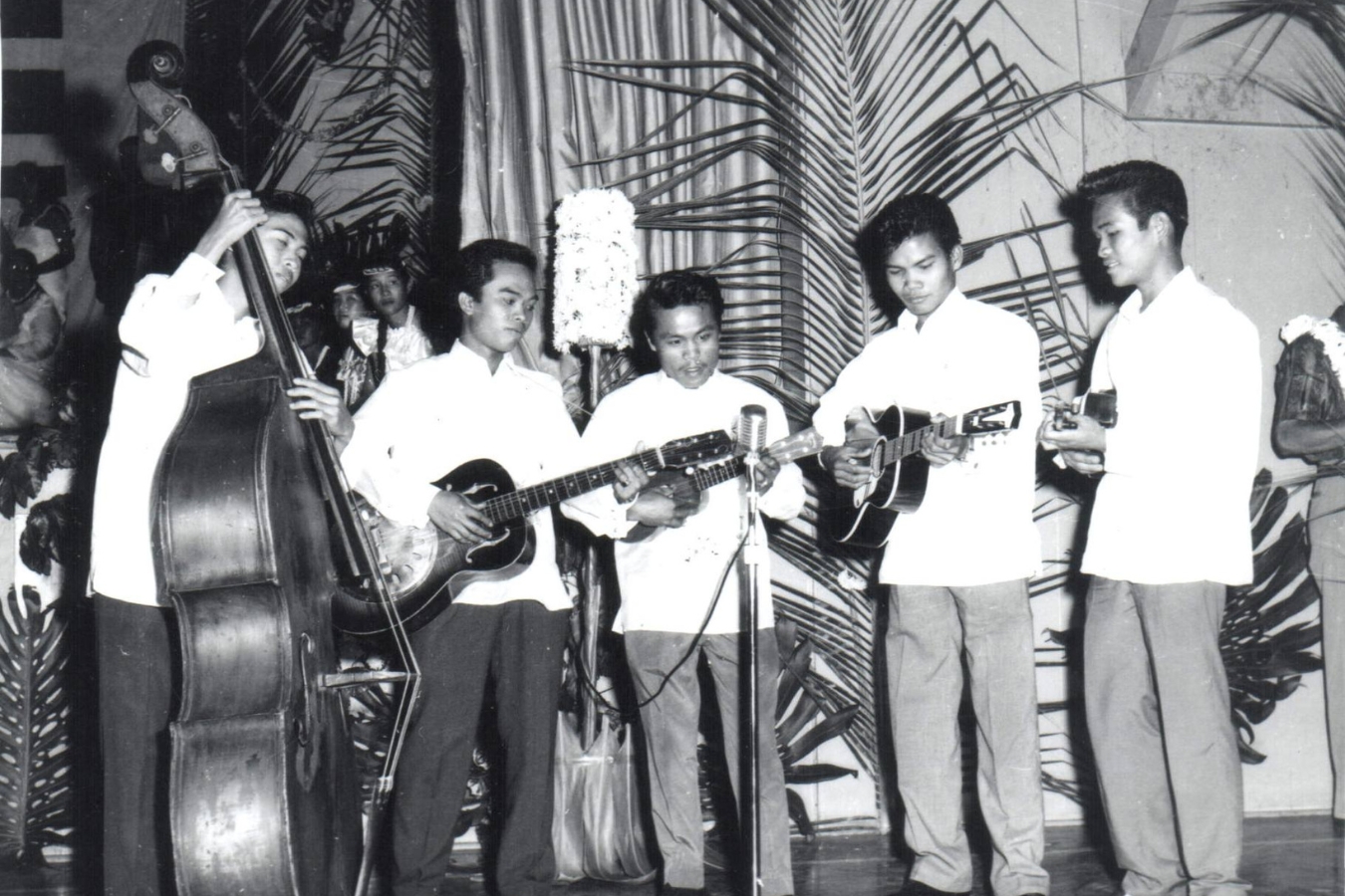 A group of men performing with musical instruments before an engaged crowd, creating a lively atmosphere.