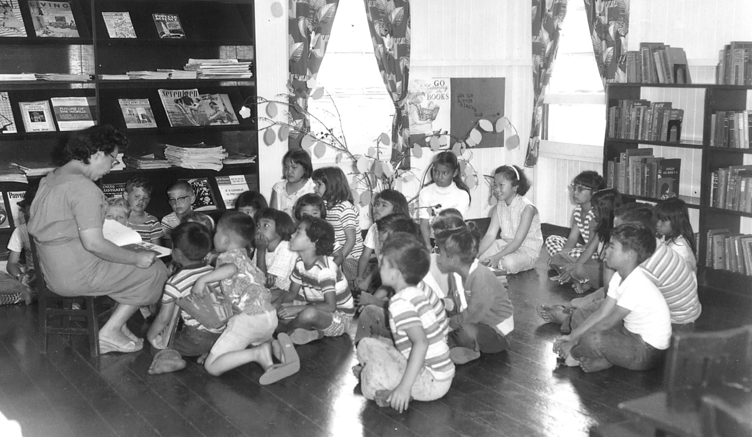 Children sitting in the library listening to a book being read.