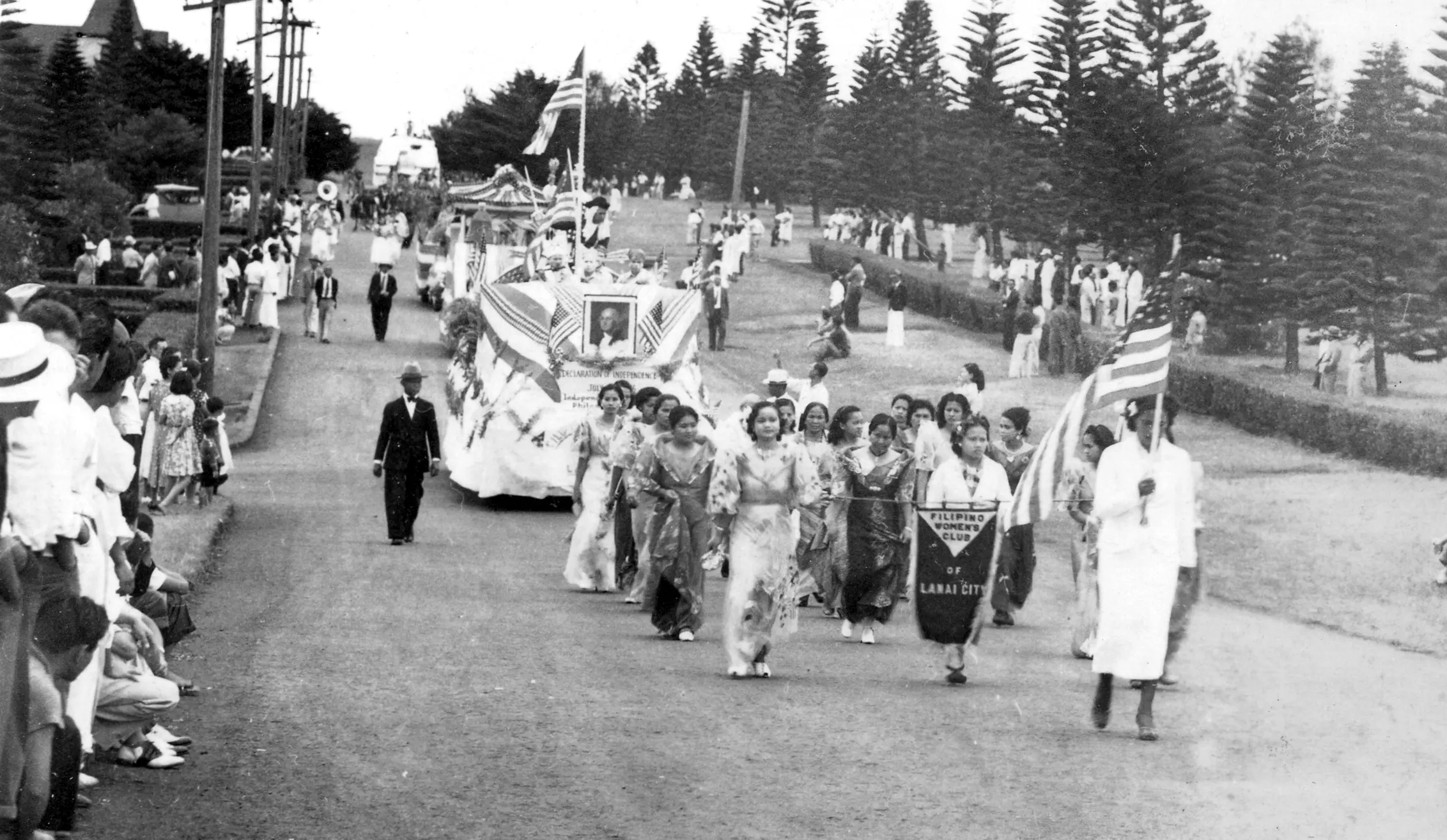 A black and white photo capturing a lively parade with people dressed in various attire.